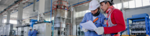Deux techniciens portant des casques de sécurité consultent des documents dans un environnement industriel - securinorme